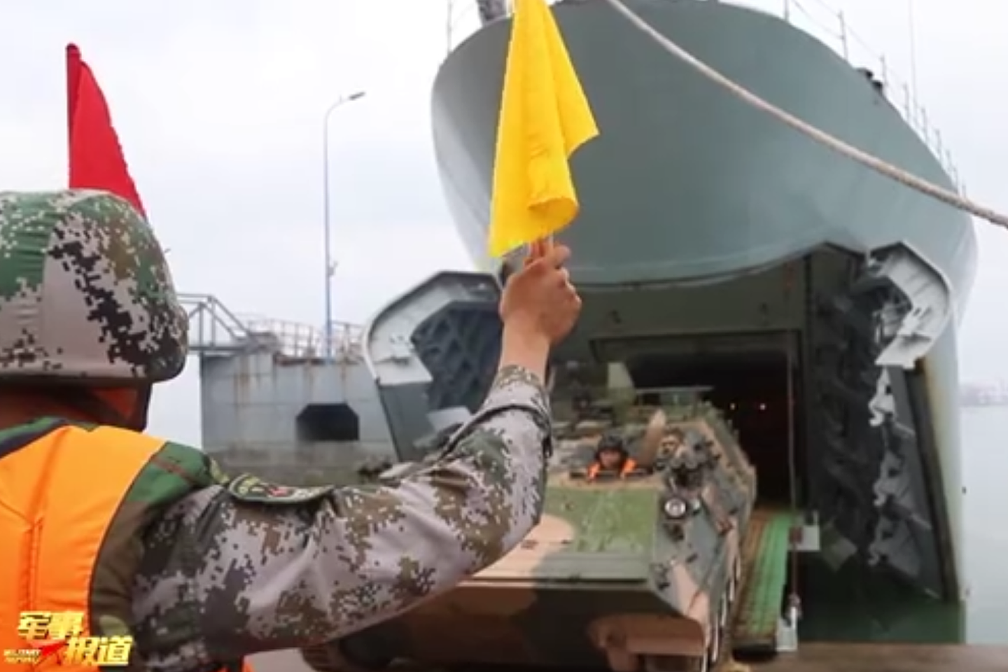 解放军东部战区两栖轮式装甲车在指挥员的指挥下驶入船舱。（中国央视《军事报道》节目视频截图）