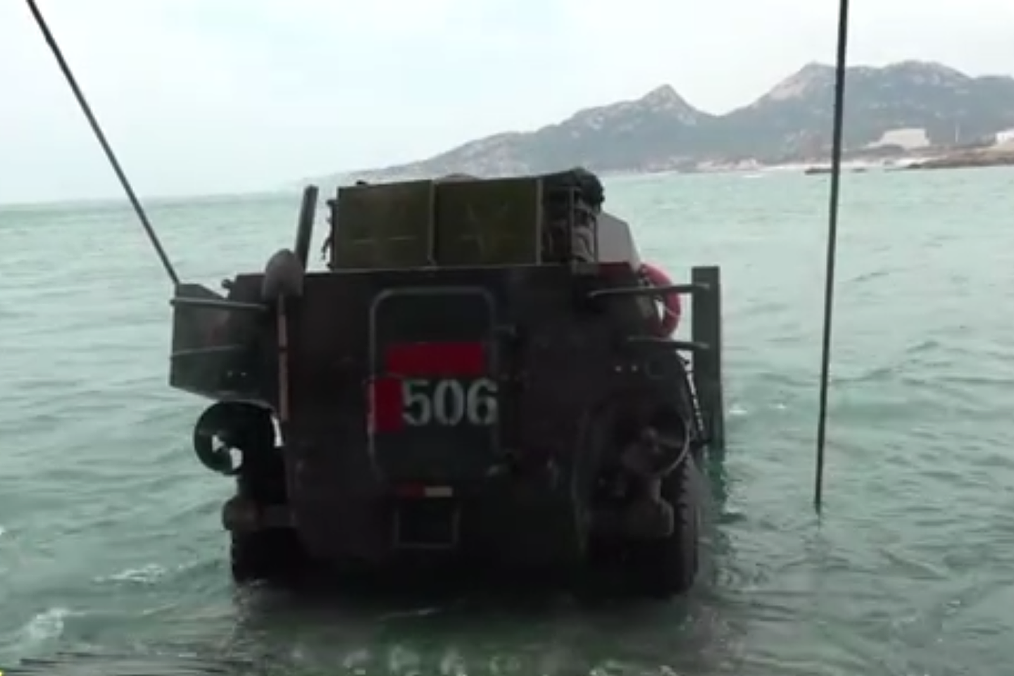 解放军东部战区两栖轮式装甲车入海。（中国央视《军事报道》节目视频截图）