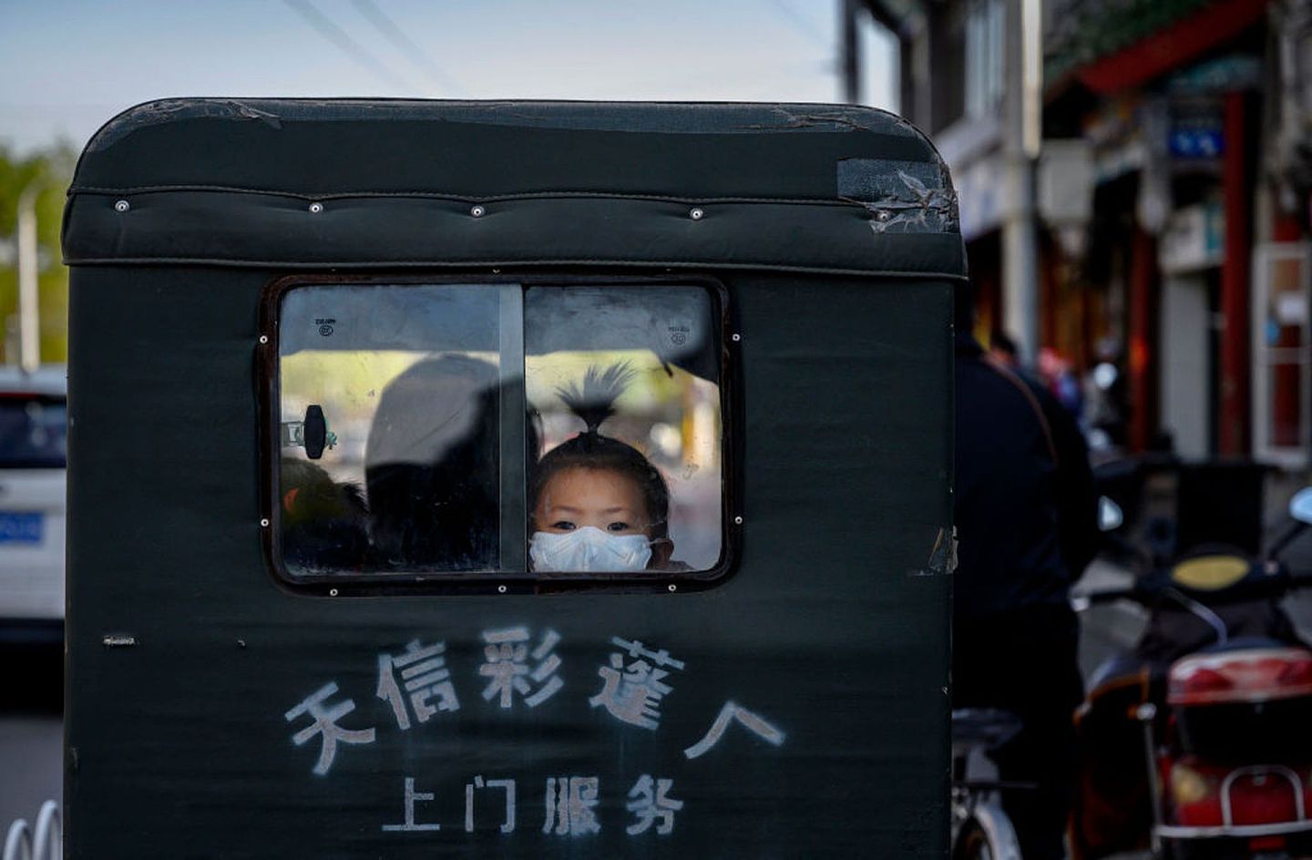 4月22日，北京街头。两位女童坐在一位长者驾驶的三轮车中。（Getty）