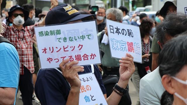 抗议民众手持标语“确诊持续扩大下办奥运是日本之耻”。