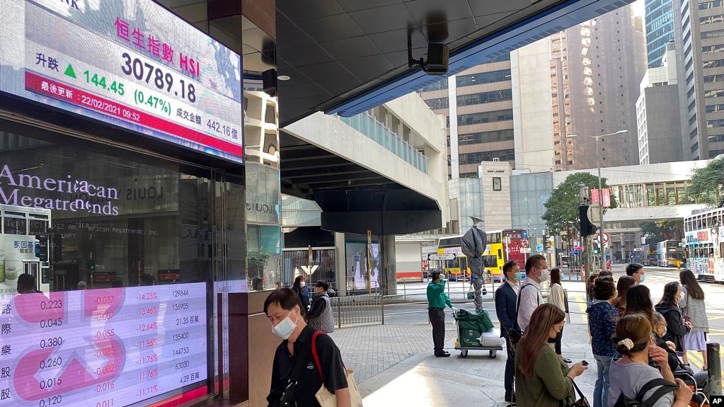 行人走过香港一家银行外的港股指数电子显示屏。