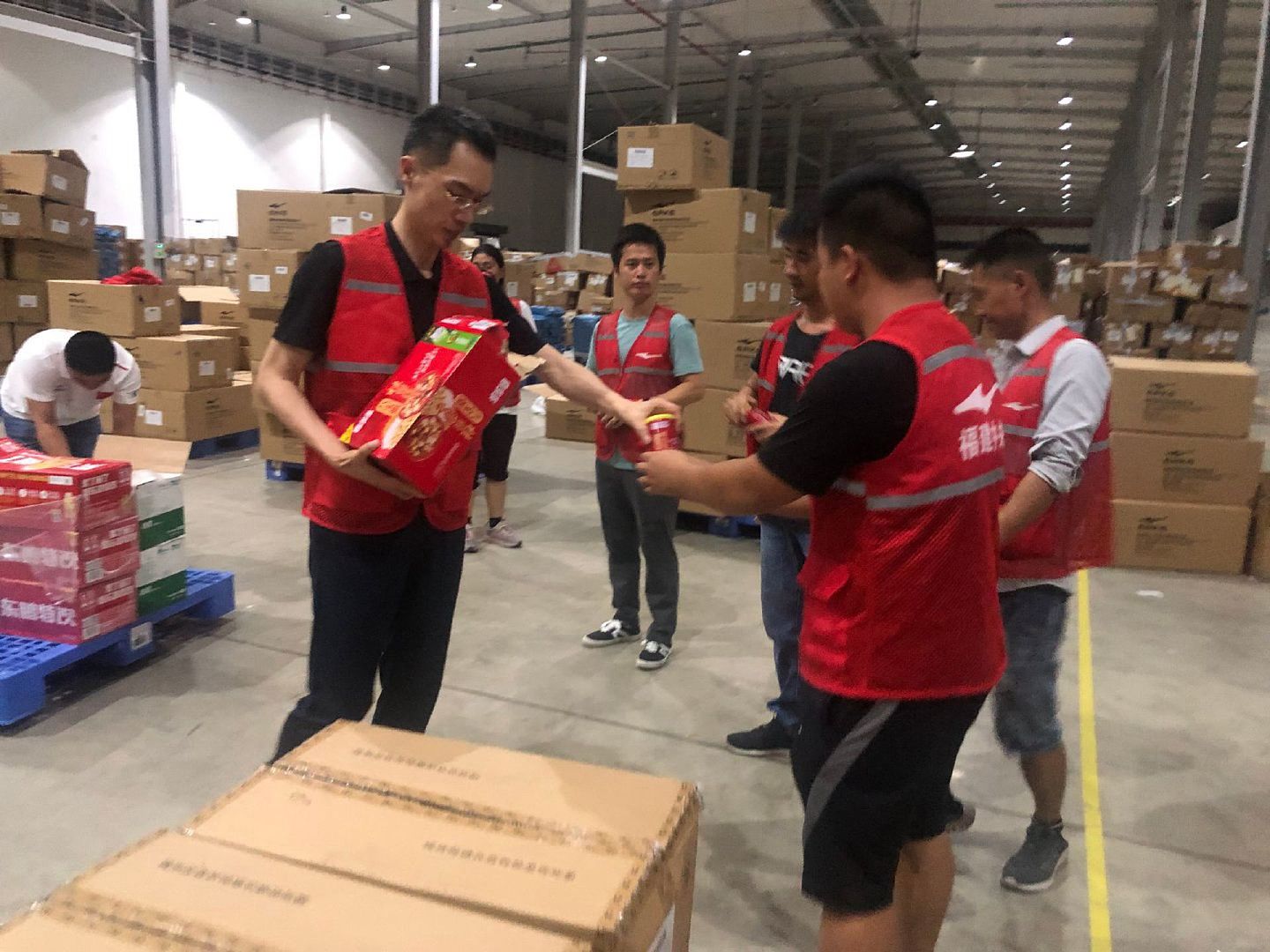 鸿星尔克董事长吴荣照（左）亲自搬运救援物资。（微博@鸿星尔克官方微博）