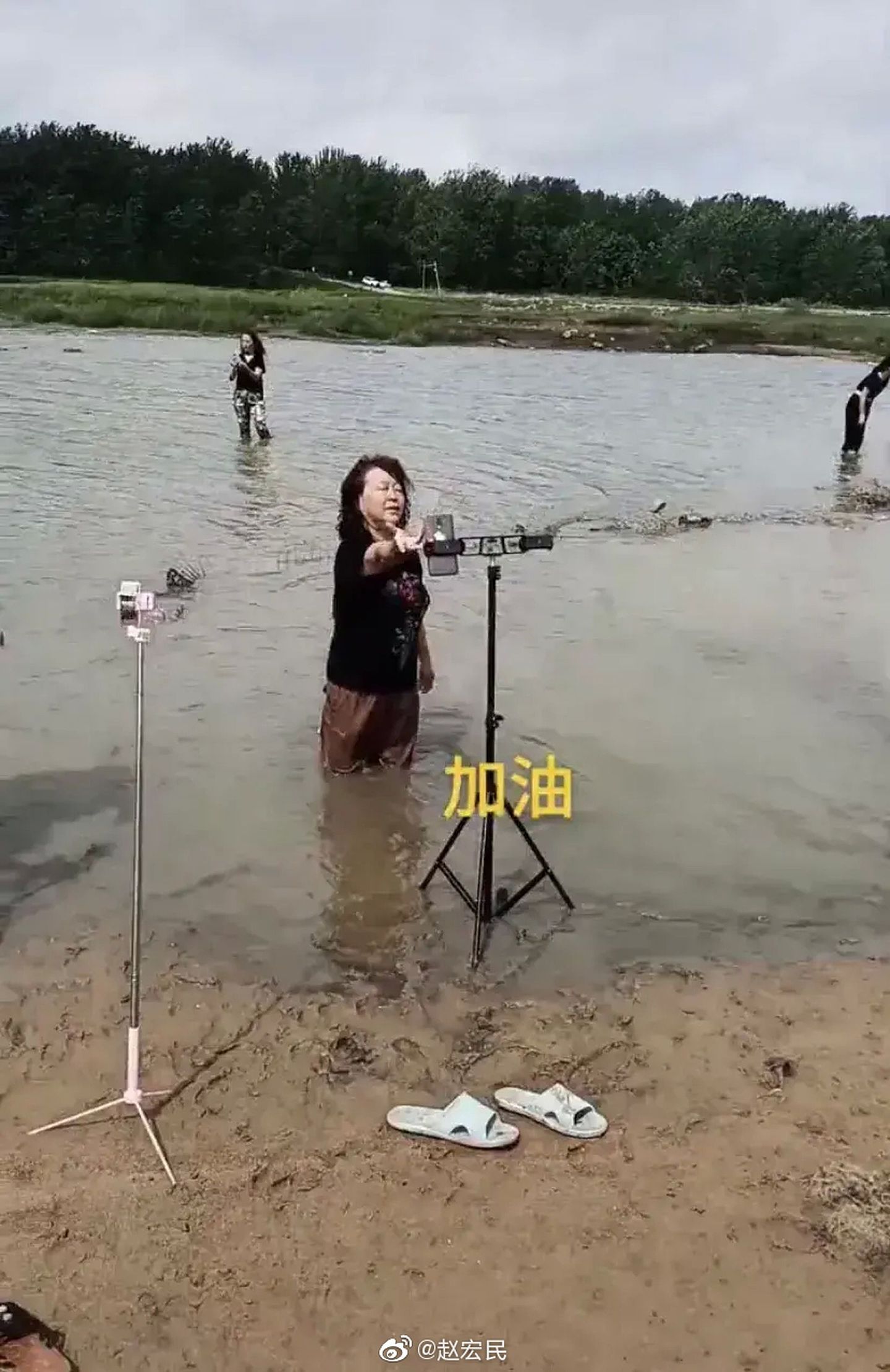 女子站在河水里进行直播。（微博@赵宏民）