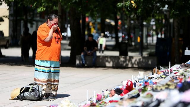 A woman mourns over 215 pairs of kids shoes outside Vancouver Art Gallery during a memorial on May 29, 2021 in Vancouver, British Columbia, Canada The remains of 215 children have been found buried at a Canadian residential school, an Indigenous band confirmed Thursday