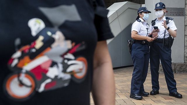 香港高等法院外两名警员站在一名身穿摩托车手造型汗衫的声援者背后（27/7/2021）