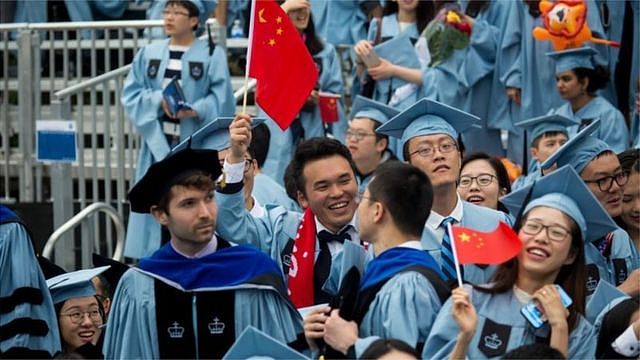 来自中国的留学生占美国留学生总数近三分之一。图为毕业生在美国哥伦比亚大学毕业典礼上手持中国国旗。
