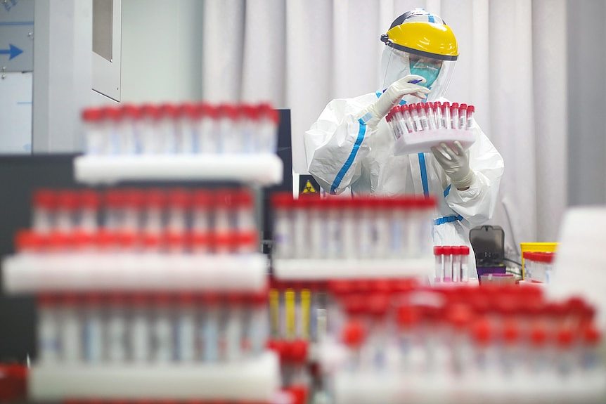 2021年7月24日，南京某医院一名穿戴个人防护装备的医务人员在检测实验室查看药瓶