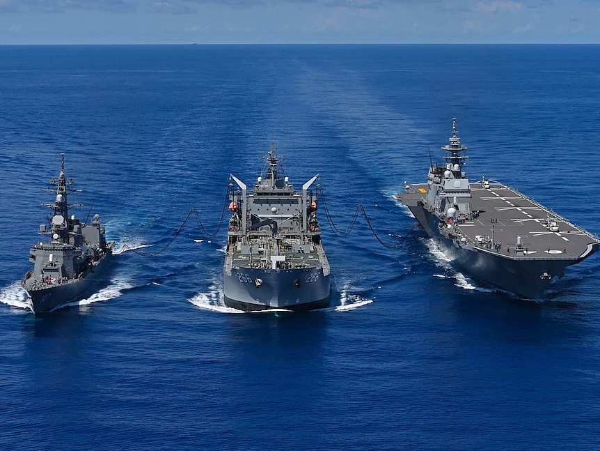 Three warships side by side in the open ocean on a sunny day