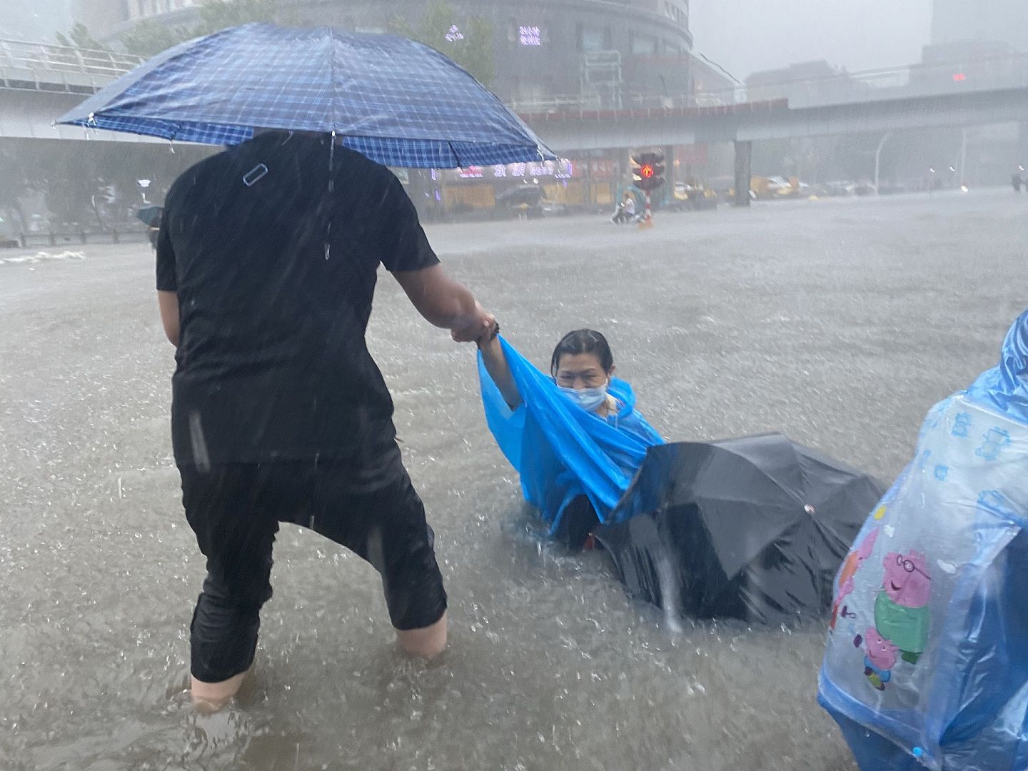 7月16日以来，强降雨造成河南省103个县（市、区）877个乡镇受灾。7月20日，暴雨下郑州市民在进行互助。（人民视觉）