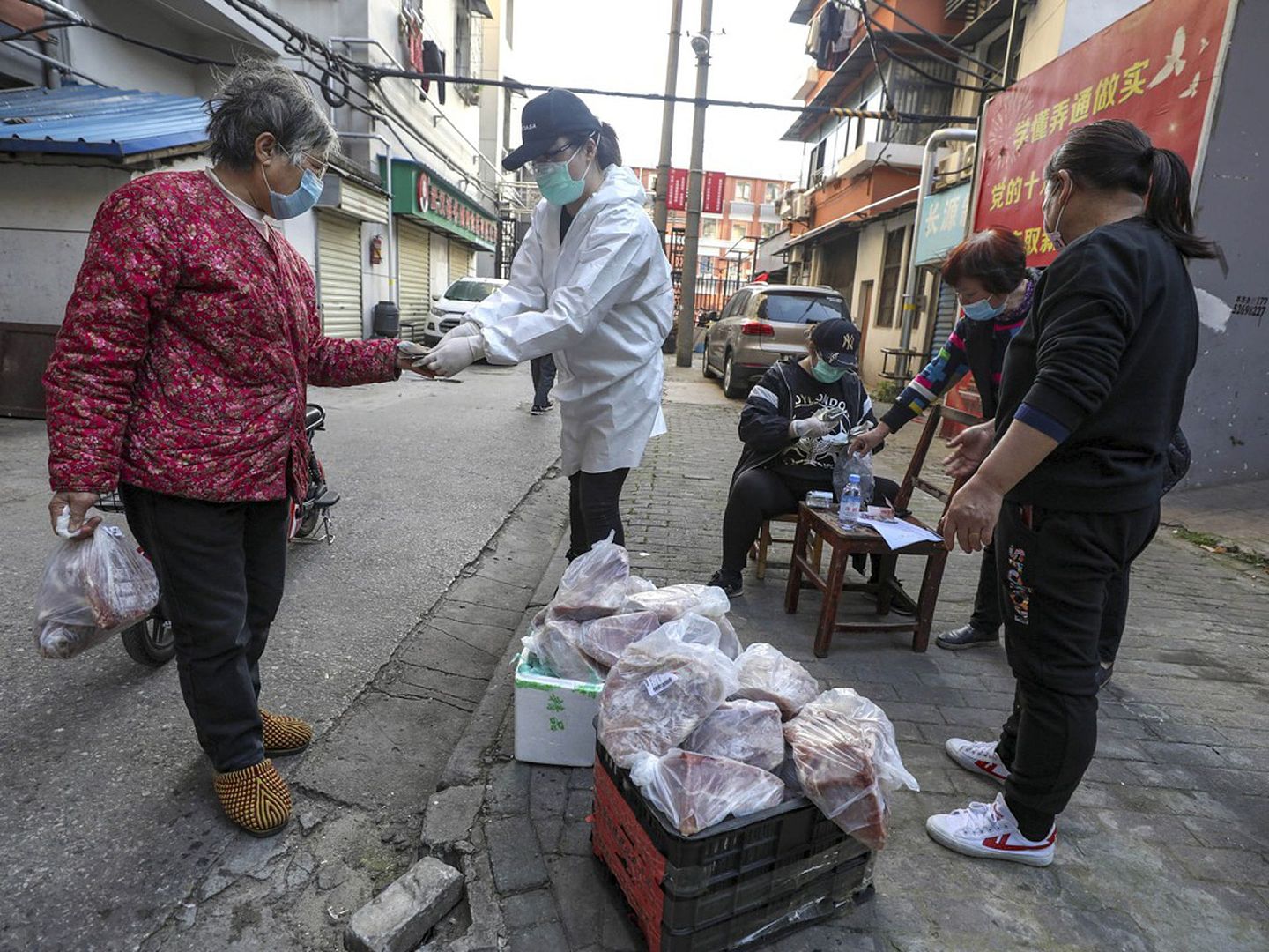 武汉的封城措施已经实施了将近两个月。图为3月18日，一些武汉市民在封闭的居民区门口排队买猪肉。（AP）