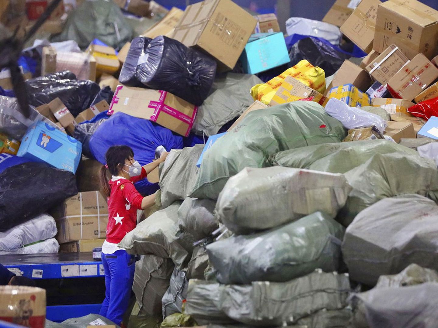 3月22日，武汉中通快递物流中心一名戴着口罩的员工在整理包裹。（Reuters）