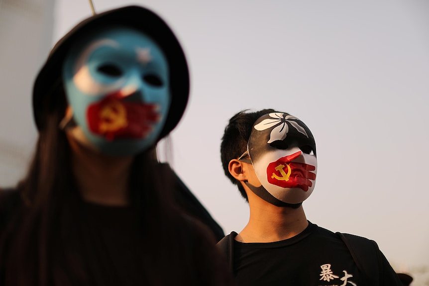 Two protesters wear masks with the Hong Kong, Commusit party and East Turkestan symbol on them.