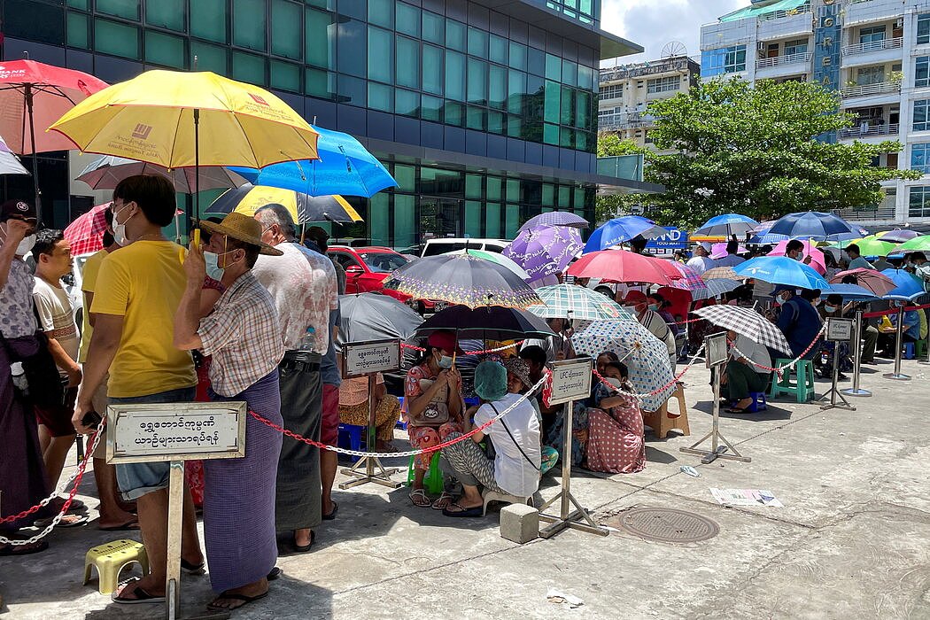 5月，仰光银行外的人们撑伞在烈日下排队。