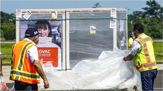 在萨尔瓦多，物流工人将装有中国产科兴疫苗的包裹装上卡车。