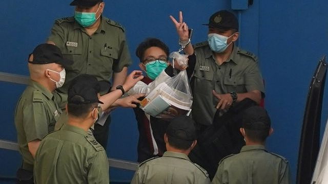 被锁上手铐的陈皓桓在狱警押送下向九龙荔枝角收押所外记者举起胜利手势（28/5/2021）