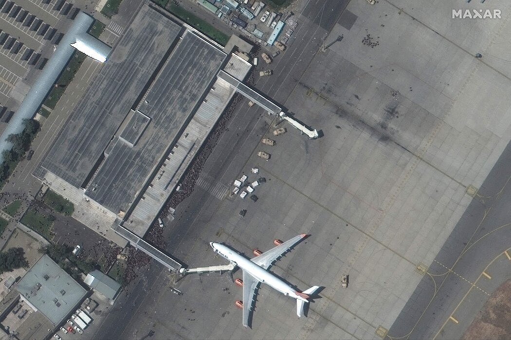 一幅卫星图像显示，周一，人群聚集在喀布尔的哈米德·卡尔扎伊国际机场的停机坪上。