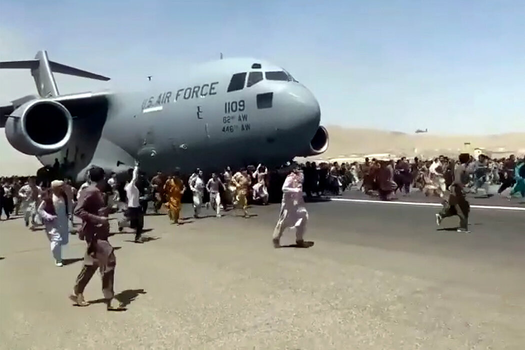 周一在喀布尔，数百人围着一架正在沿着跑道移动的美国空军C-17运输机一起奔跑。