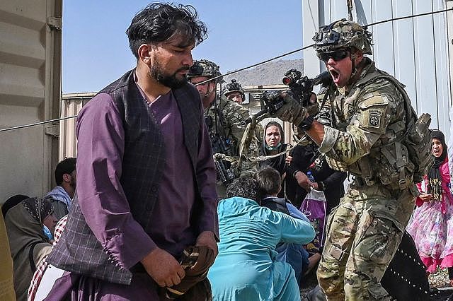 A US soldier points his gun towards an Afghan passenger at the Kabul airport in Kabul on 16 August 2021