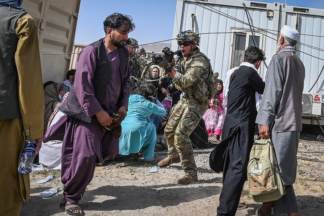 一名美国军人用枪指着一名阿富汗男子，成千上万的人涌入喀布尔机场，试图逃离被塔利班占领的阿富汗。
