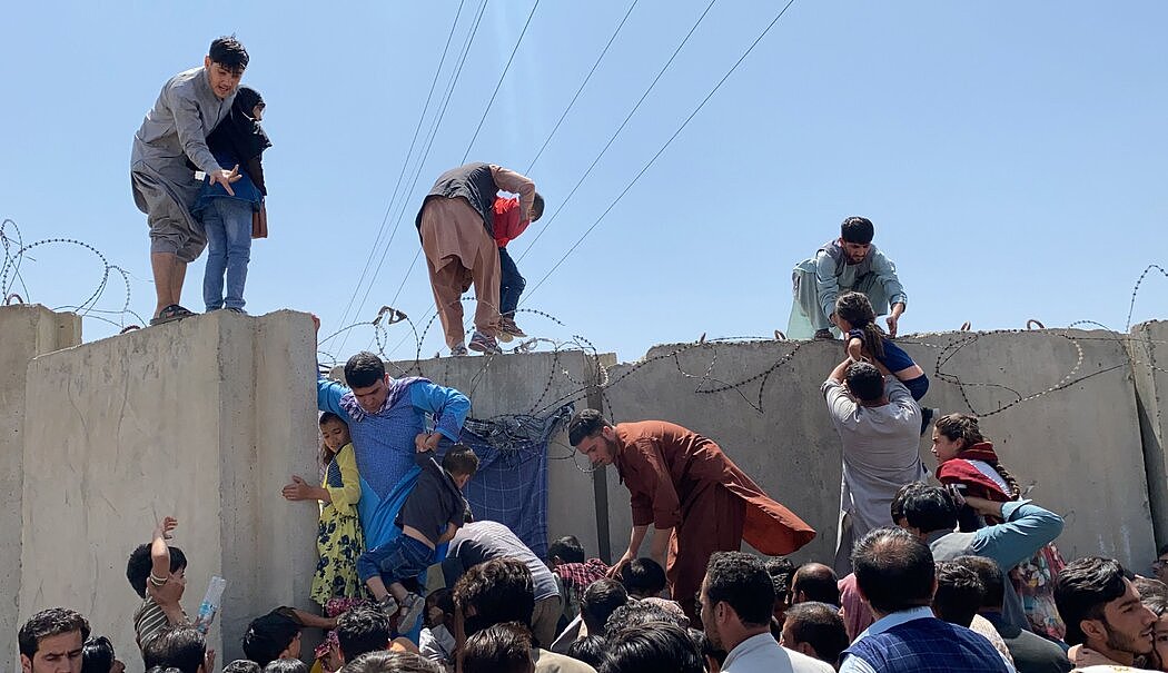 塔利班控制阿富汗首都喀布尔后，人们拼命越过哈米德·卡尔扎伊国际机场的边界墙逃离阿富汗。