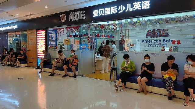 Parents wait outside a children's English early education training store in Shanghai, Aug. 20, 2021.