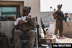 美国海军陆战队公布的照片显示，在喀布尔哈米德·卡尔扎伊国际机场的撤离行动期间，一名海军陆战队员抱着一名婴儿。(2021年8月20日)