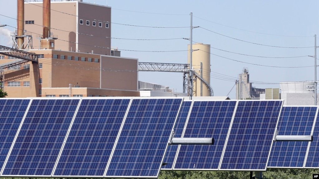 资料照片：内布拉斯加州弗里蒙特的一组太阳能电池板，后面可见一家发电场。(2018年5月31日)