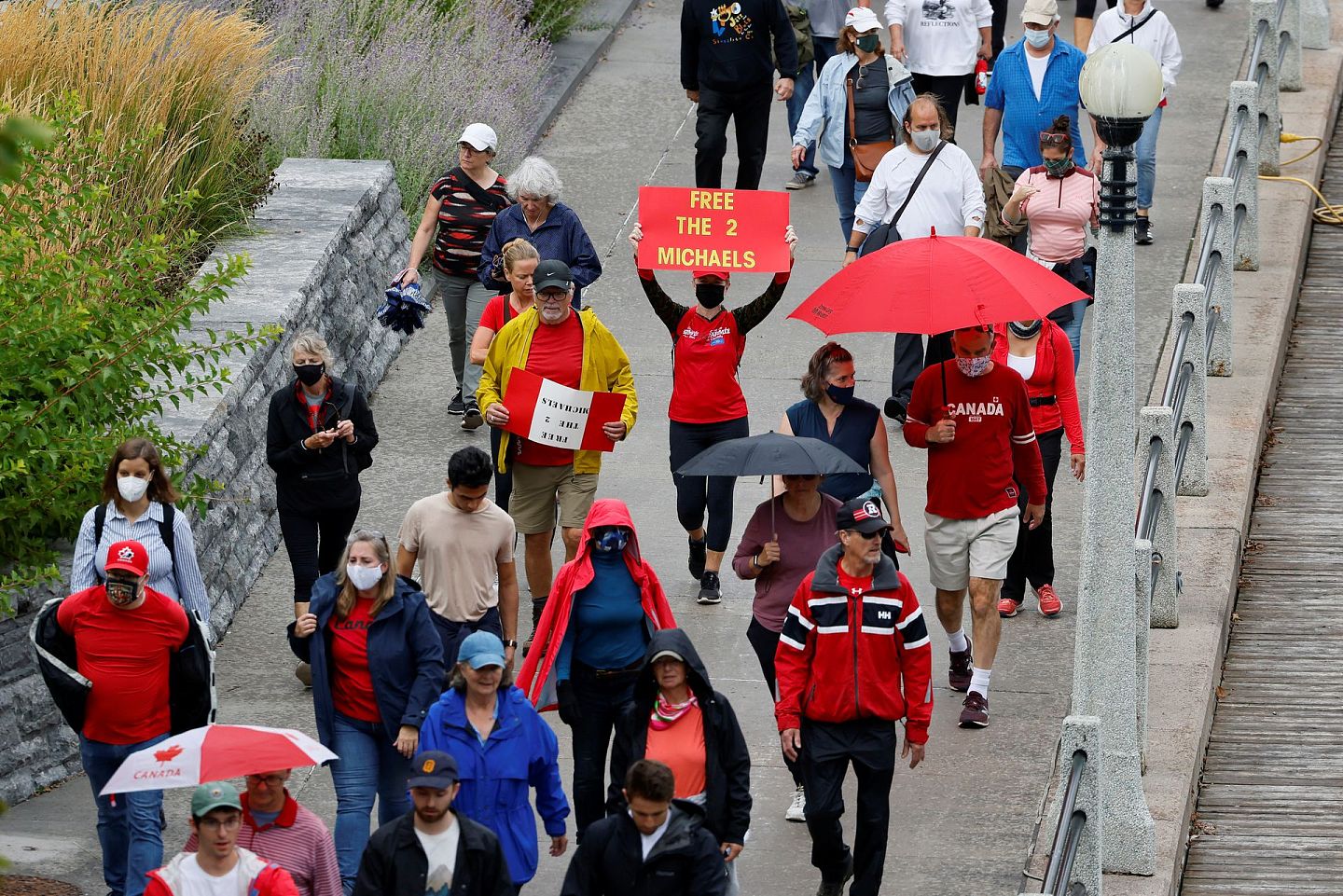 数百人聚集在渥太华的一个公园，一些人穿着印有“为迈克尔兄弟游行”、“为自由走7,000步”的白衬衫，举着“把他们带回家”的横幅。（Reuters）