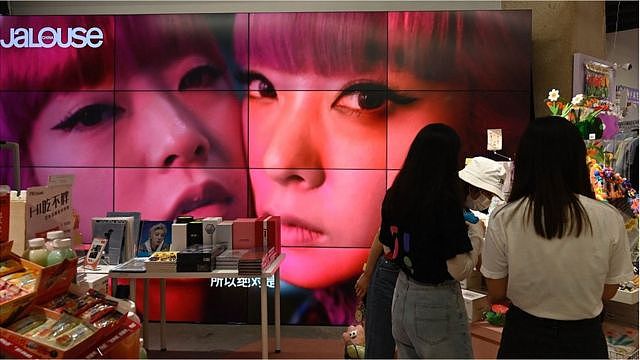A screen shows a video of overseas celebrity idols at a fan merchandise store at a shopping mall in Beijing on September 2, 2021.