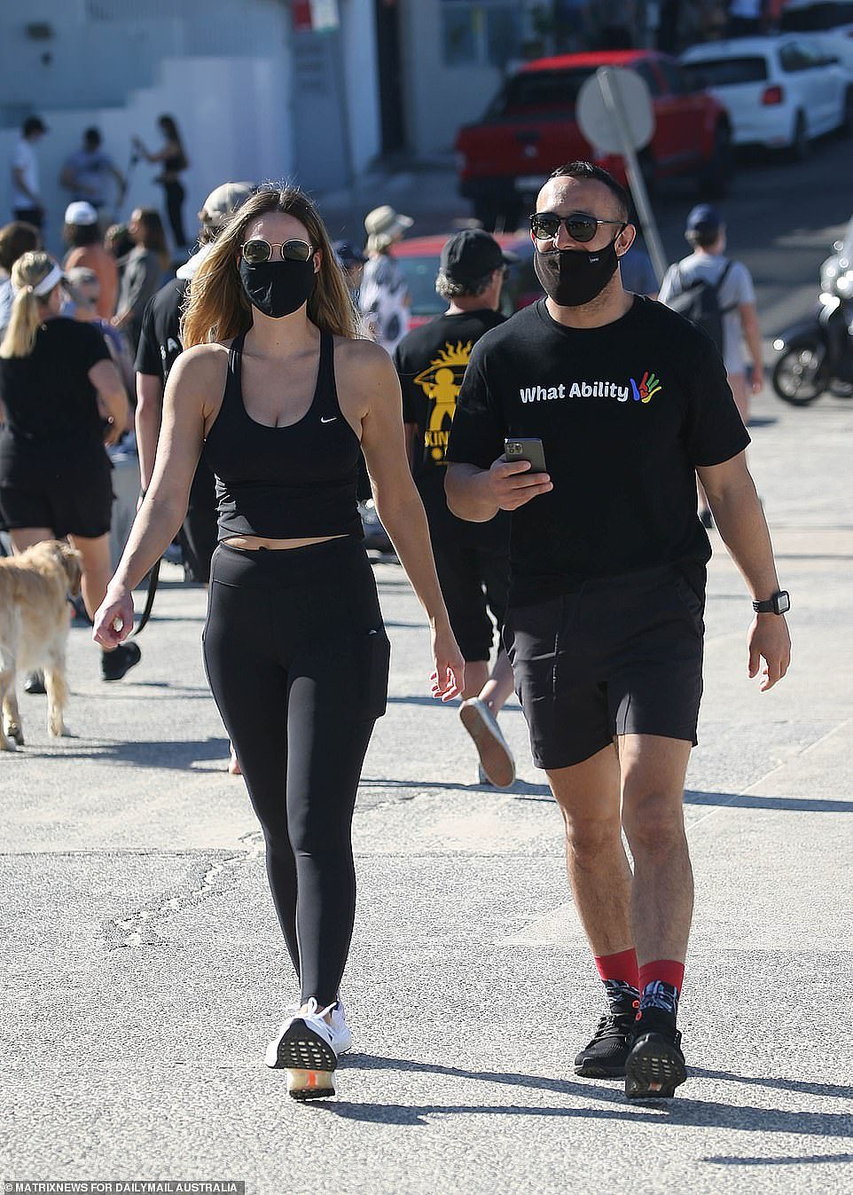 Two Sydney residents are seen walking along the promenade at Bondi Beach during a sweltering hot day on Saturday