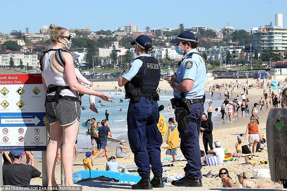 A mother is seen speaking to police as thousands race to the beach in Bondi