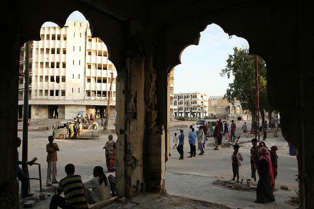 2007年1月，索马里首都摩加迪沙，人们在一座被战争毁坏的废弃建筑外等车。