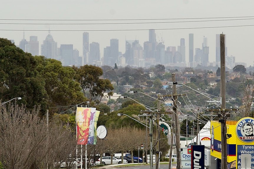 The CBD skyline of towers is visible from an elevated suburban road, on an overcast wintry day.
