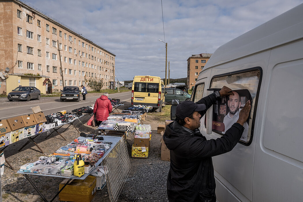摩尔曼斯克地区的一个乡村市场里，一个人在自己的汽车上贴了朋友的竞选海报。许多反对派候选人被取消了资格。