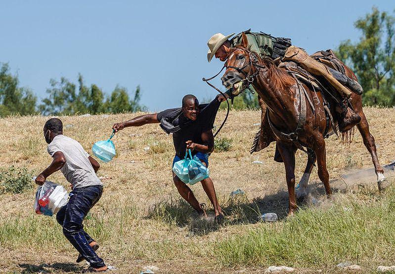美墨边界的联邦巡逻员警19日骑马在格兰德河畔，挥绳围堵涉水非法入境的海地难民。 (Getty Images)