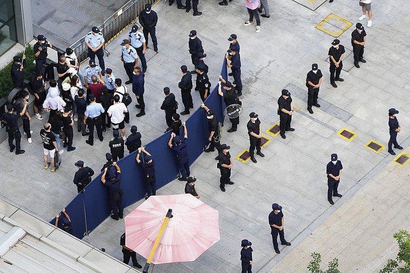 23日投资者试图进入恒大集团深圳总部时，被警察和保安人员包围。 （美联社）