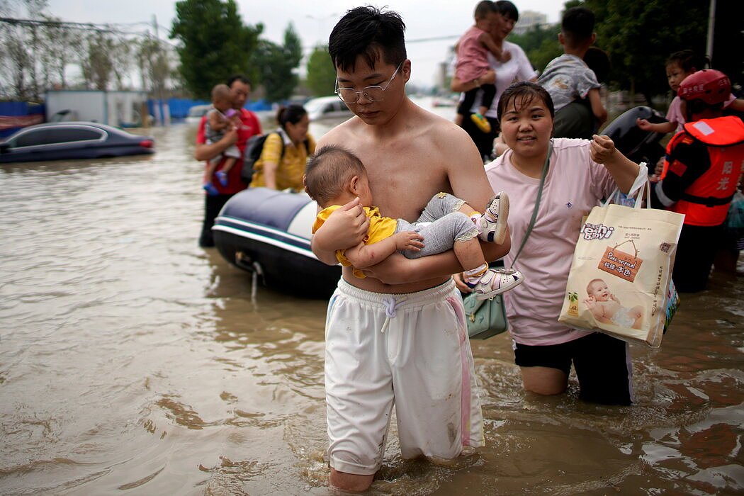 在郑州街头涉水的人们。至少300人在洪水中丧生。