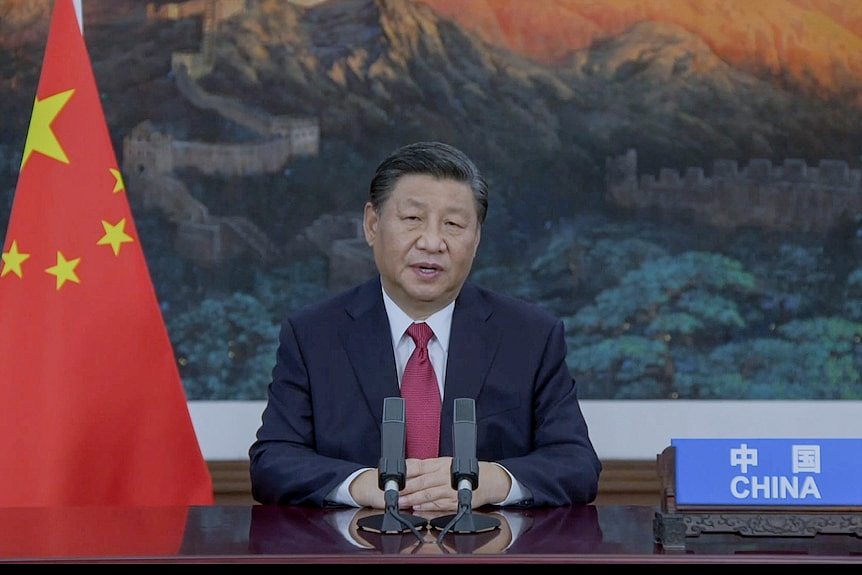 中国国家主席习近平在联合国大会上发表讲话，身旁是中国国旗