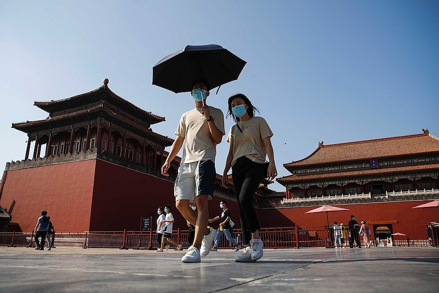 一对戴着面具的男女在北京故宫散步。