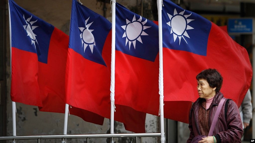 资料照：一名妇女走过台北街道旁飘扬的台湾旗帜。