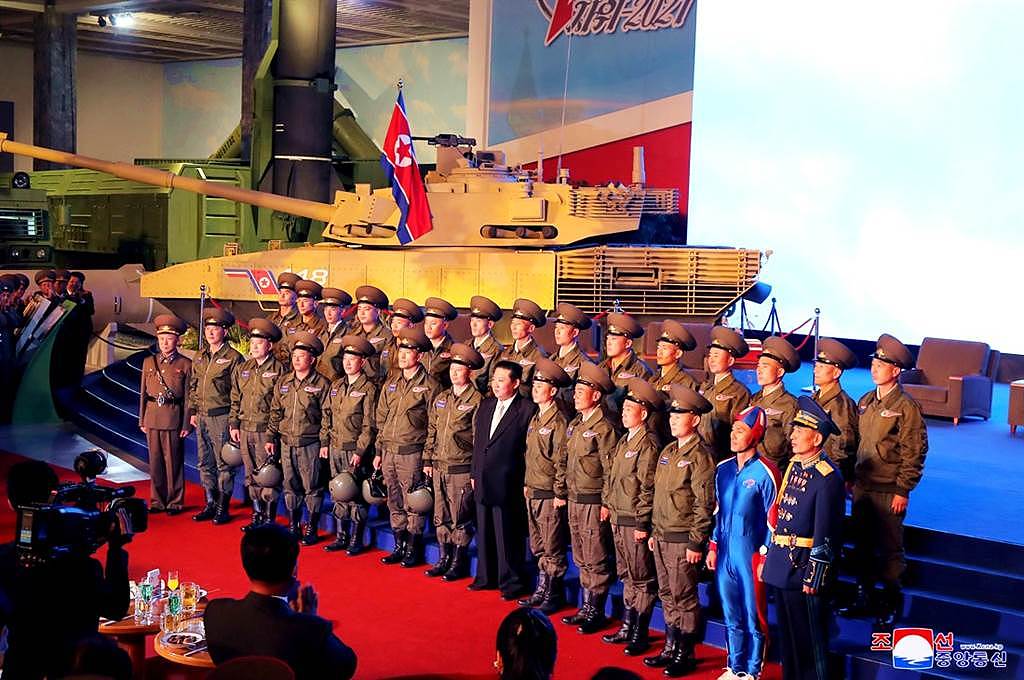 11日北韩国防展览会上，金正恩的风采被第一排右边穿着亮蓝色紧身衣的男子抢走。 （图／路透社、北韩朝中社）