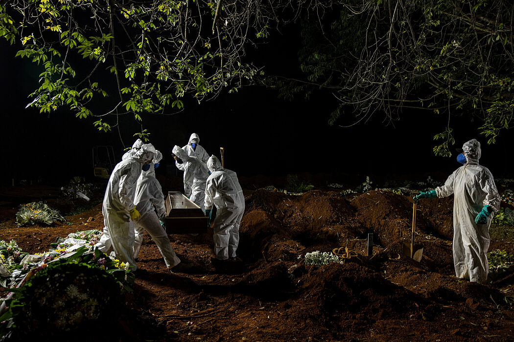 4月，圣保罗一家公墓的工作人员抬着一口新冠死者的棺木。