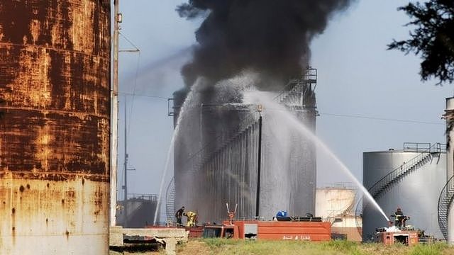 Fire fighters spray jets of water at a petrol storage tank at the Zahrani Oil Installation in southern Lebanon (11 October 2021)