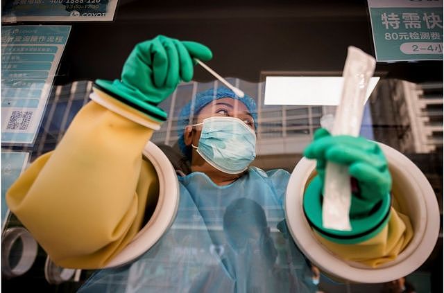 一名医护人员在北京街头的一个摊位上进行核酸检测。
