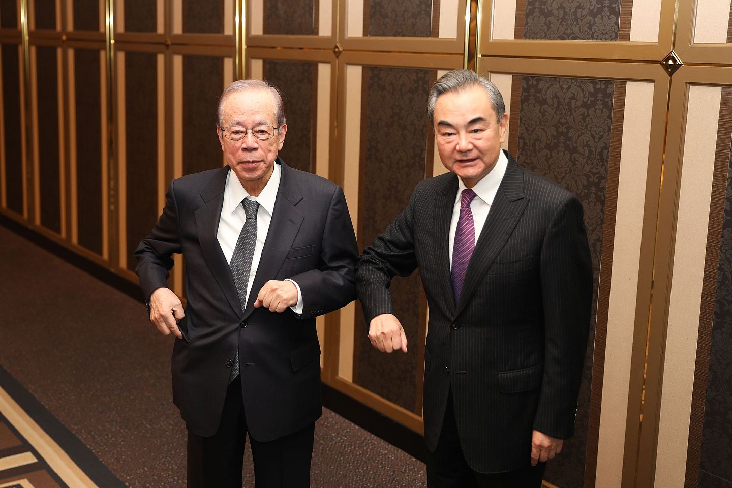 2020年11月25日，中国外长王毅（右）在东京与日本前首相福田康夫会晤，两人碰肘致意。（新华社）