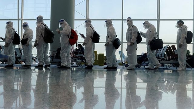 香港国际机场内一群身穿医用个人防护衣（PPE）的旅客排队准备登机（9/7/2021）