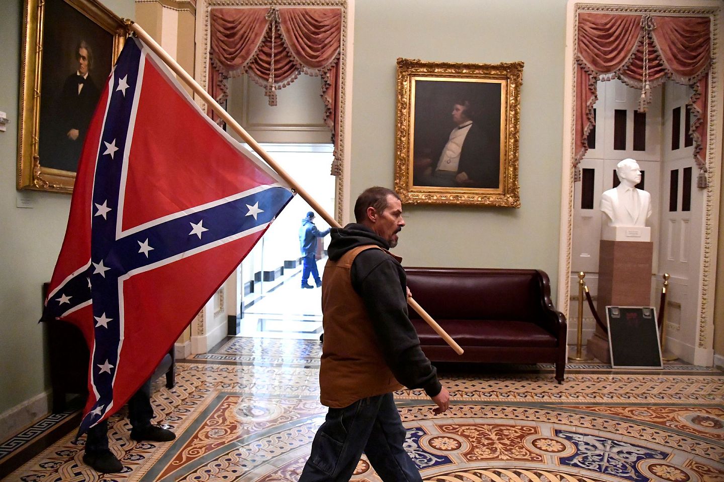 2021年1月6日，美国华盛顿，特朗普的支持者在突破安全防线后，在参议院入口附近的美国国会大厦二楼举着南方邦联战旗。（Reuters）