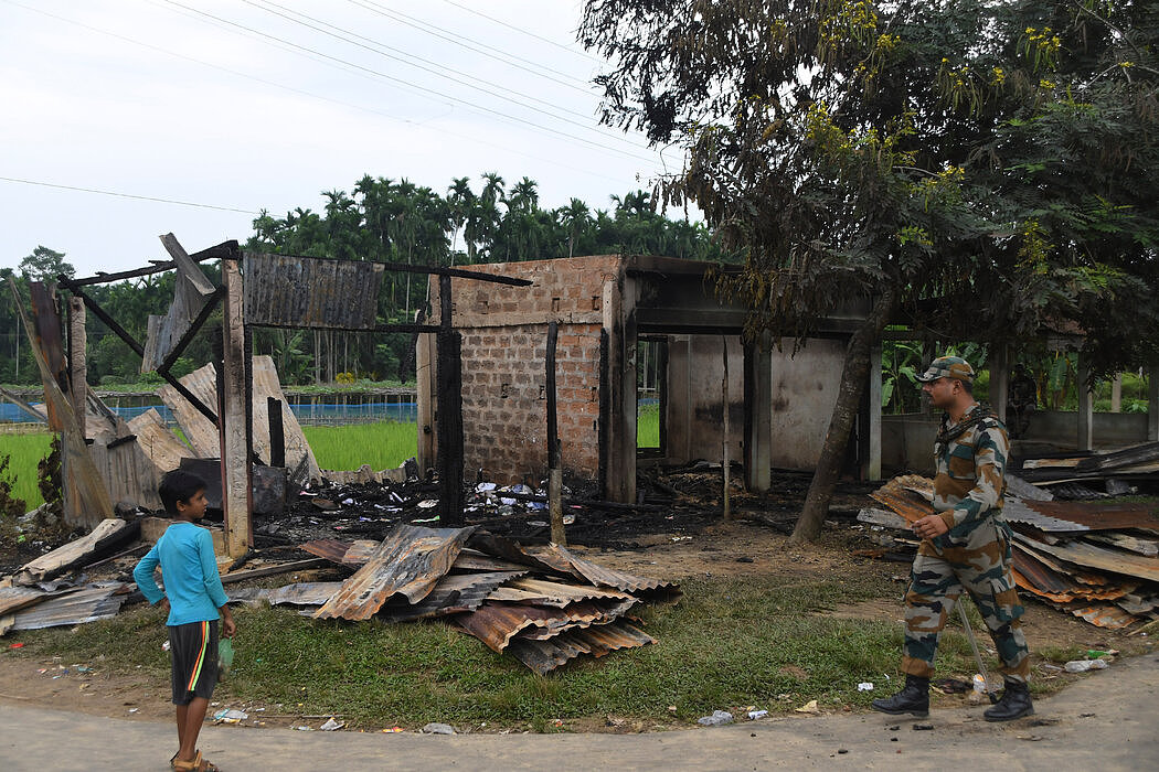 上个月，在印度东北部的特里普拉邦，一名准军事人员在一家被烧毁的商店附近巡逻。