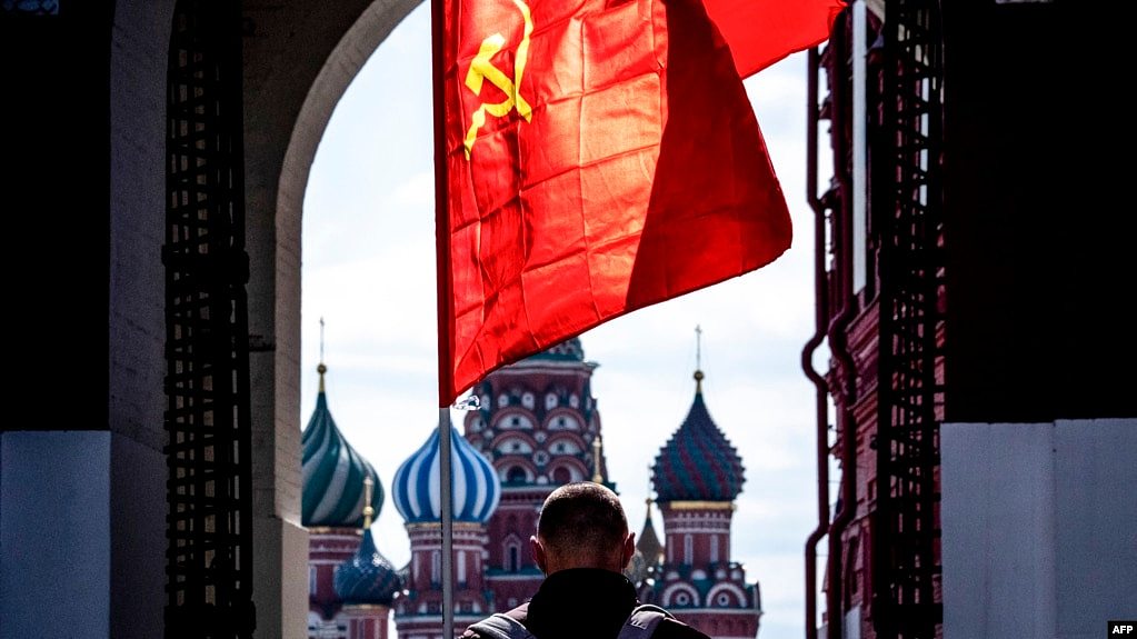 资料照：在莫斯科红场，一名俄罗斯共产党的支持者举着一面苏共的旗帜。（2020年5月1日）