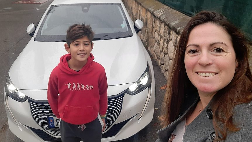 A brunette woman and a young boy before a new white car